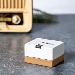 A box of Crawly Earphones in white and brown, set against a vintage radio on a grey surface.