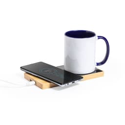 A wireless charger with a wooden base, featuring a smartphone and a white mug with a blue handle.