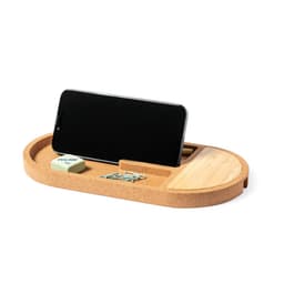 A cork wireless charger in an oval shape with a smartphone resting on it, featuring a wooden section and some accessories.