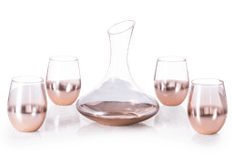 A glass decanter with a sleek design, accompanied by four rose gold-hued stemless wine glasses.