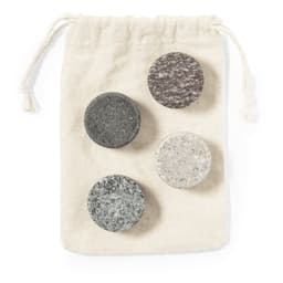 A drawstring bag containing four circular stone ice cubes in grey and white shades.