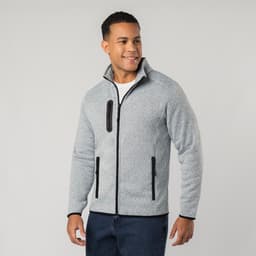 A man wearing a grey polar fleece jacket with black zippers and a collar, smiling at the camera.