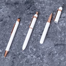 A collection of white metal pens with rose gold accents, including a ballpoint and a stylus, displayed on a grey surface.