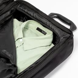 A wheeled black bag with a green shirt inside, featuring a handle and an interior compartment.