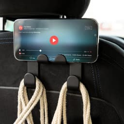 A car phone holder in black, mounted on a car seat, holding a smartphone displaying a video.