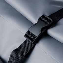 A grey dry bag featuring a secure black buckle and straps for fastening. It has a simple, waterproof design.