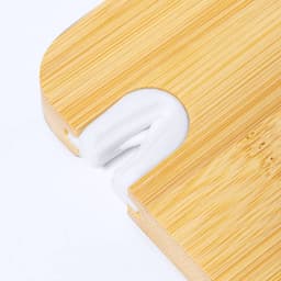 A bamboo chopping board featuring a white silicone grip. The board has a rounded edge with a cutout.