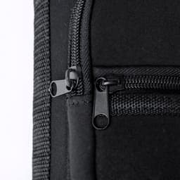A drink bottle with a black exterior featuring zippers and textured fabric details.
