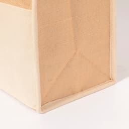 A cooler bag in natural tones, featuring a sturdy base and a textured surface. It has a logo on the side.