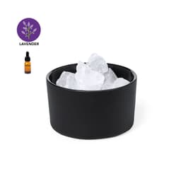 A black bowl filled with clear crystals, accompanied by a small amber bottle of lavender essential oil.