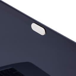 A black laptop screen with a small, round adhesive tab at the top. The tab is light in colour and has a textured surface.