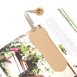 A tag bookmark in a neutral colour with a decorative top, attached to a decorative clasp.