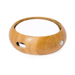 A round bamboo charging dock with a white surface and a small connector opening, designed for electronic devices.