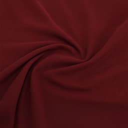A close-up of burgundy fabric showing a smooth, soft texture with subtle folds. There is a logo present.