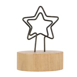 A star-shaped metal holder on a wooden base for displaying notes or photos. The base is light in colour.