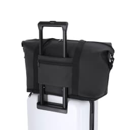 A black duffel bag with handles, resting on top of a white suitcase, featuring a zippered pocket.