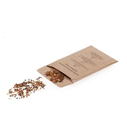 A brown kraft packet of seeds with some seeds scattered beside it. The packet features a logo.