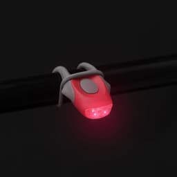 A red bike light set featuring a compact design with a grey securing strap. It has a logo on the side.