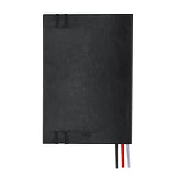A black Suran Notebook with a sleek design, featuring two straps and three ribbon bookmarks in red, white, and black.