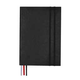 A black notebook with a textured cover, featuring elastic closures and coloured ribbon bookmarks.
