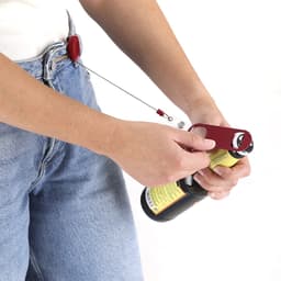 A drink bottle opener in red, attached to a retractable cord, used to open a beer bottle.