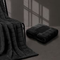 A plush, dark grey blanket draped over a chair, with a neatly folded version resting on the floor nearby.