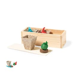 A wooden box containing biodegradable seed pots in brown, with red and blue markers, and a green seed shape.