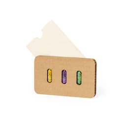 A cardboard gift set containing three colourful seed capsules in yellow, purple, and green, with a blank white card.