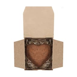 A heart-shaped chocolate in a brown cardboard box, surrounded by shredded paper for packaging.