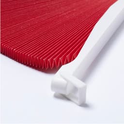 A red pleated folding fan with a white handle, positioned neatly on a light background.