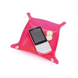 A pink Flot Coin Tray with a mobile phone and two coins placed inside. It features rounded corners and a glossy finish.