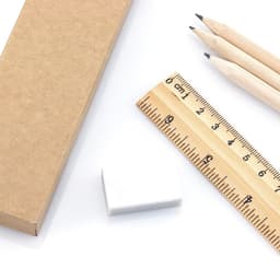A kraft box containing a white eraser, a wooden ruler, and three wooden pencils.