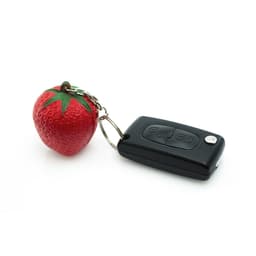 A red strawberry-shaped stress keyring attached to a black remote-like key fob with buttons.