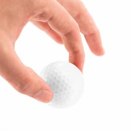 A hand holds a white golf ball featuring a dimpled texture, with visible branding.