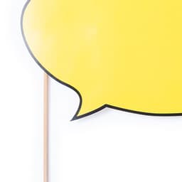 A yellow speech bubble prop mounted on a wooden stick, featuring a black outline.