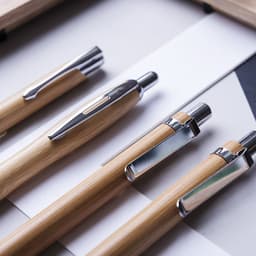 A collection of wooden pens with metallic accents, featuring various designs and a neutral colour palette.