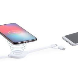 A white wireless charger with a smartphone placed on it, featuring a spiral design and a charging cable nearby.