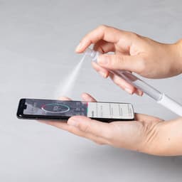 A hand holding a white spray pen over a smartphone, displaying a circular graphic on the screen.