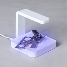 A wireless charger in white with a modern design, featuring keys placed on its charging surface.