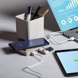 A desk setup featuring a pen holder with pens, a smartphone on a charging dock, and connected devices.