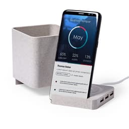A mobile phone on a charging dock with a plant holder. The dock is light grey and includes multiple USB ports.