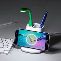 A white multifunction pencil holder with a green light, two pens, and a smartphone. It features a logo.