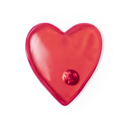 A heart-shaped heat pack in vibrant red, featuring a small central disc. It has a smooth, glossy exterior.