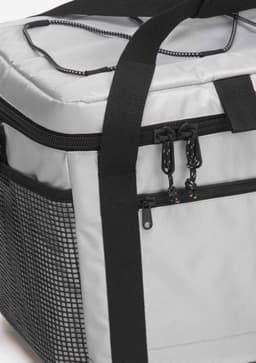 A grey cooler with a black mesh side pocket and sturdy handle, featuring zippers and straps for easy transport.