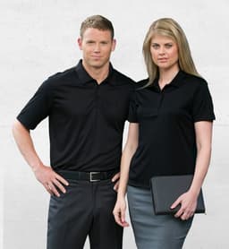 A black men's polo shirt worn by a man and a matching black polo worn by a woman, both with a subtle ribbed design.