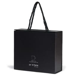 A black box with a handle, containing an espresso set, featuring a logo on the front.