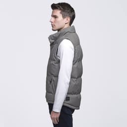 A grey puffer vest displayed on a male model, featuring a high collar and a logo tag.