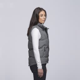 A grey puffa vest features a zip front and side pockets, worn over a long-sleeve white top.