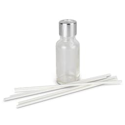 A glass scented diffuser bottle with a silver lid and five white reeds arranged beside it.