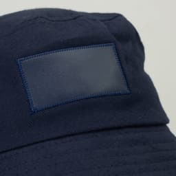 A navy bucket hat featuring a patch area and a logo. Ideal for headwear with a wide brim.